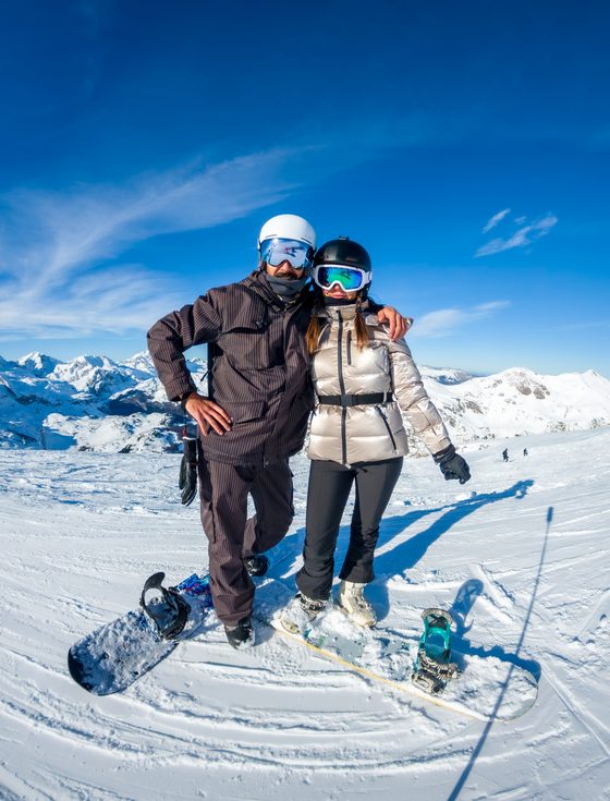 A couple in ski gear standing on a snow covered mountain slope